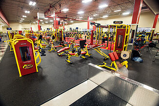 View of the machine area at Retro Fitness Stroudsburg. The machines rest on REGUPOL aktiv flooring that matches the brand colors and theme.