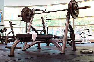 A weight bench with weights on it in Temple University's fitness center, positioned on REGUPOL aktipro rubber flooring.