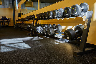 View of the dumbbell weight rack in the Millersville University performance center. The rack sits on REGUPOL aktivpro roll flooring in the color "Gray Hound"