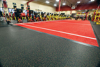 REGUPOL aktiv flooring transitions into red themed turf to match Retro Fitness's theme.