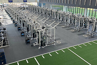Penn State University Football Strength and Conditioning Facility Aerial view of a spacious strength and conditioning facility with weightlifting equipment, turf area and REGUPOL aktivpro roll flooring with crash zones.