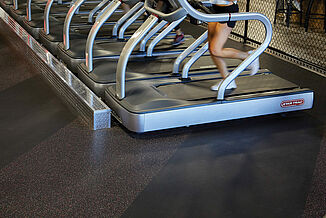 UFC Gym - Front of Treadmills and REGUPOL aktiv Flooring The front angled view of a row of treadmills resting on REGUPOL aktiv rolled rubber flooring in the UFC Gym located in Lancaster. An athlete is in motion on the treadmill.