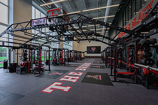 Full view of Texas Tech football weight room, showcasing the weight training racks and free weight area.