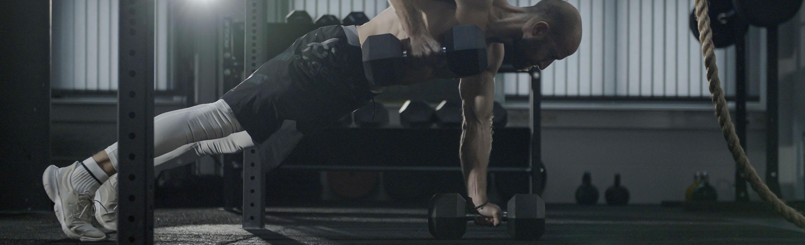 A man is weight training in a facililty on REGUPOL rubber floors that feature sonusfit m 520, helping to reduce sound vibrations.