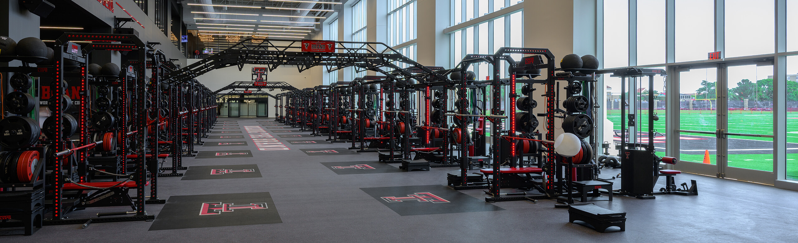 View of entrance of Texas Tech Football weight room, showcasing the number of weight training racks and REGUPOL crash platforms.