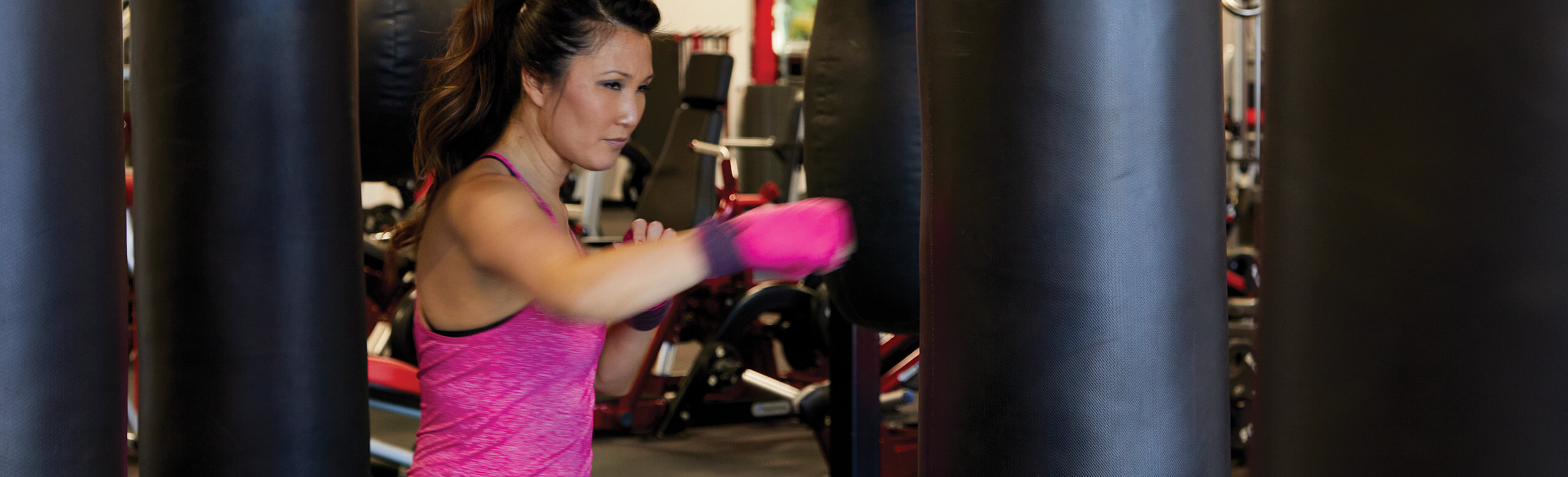 UFC Gym - Punching Bag and REGUPOL aktiv Flooring A woman at the UFC Gym trains her skills as she punches a punching bag. She is standing atop REGUPOL aktiv rolled rubber flooring.